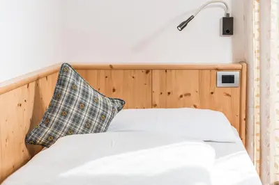 a bedroom with a white bed with a blue pillow at Villa Scherlin in Ortisei