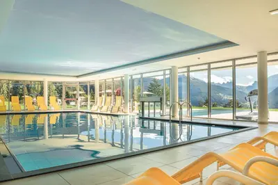 a house with a pool with chairs and mountains at Villa Scherlin in Ortisei