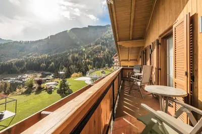 a balcony with a table and chairs and mountains at Villa Scherlin in Ortisei