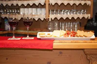 two glasses of wine and a plate of food on a table at Aparthotel Wellness Villa di Bosco in Tesero