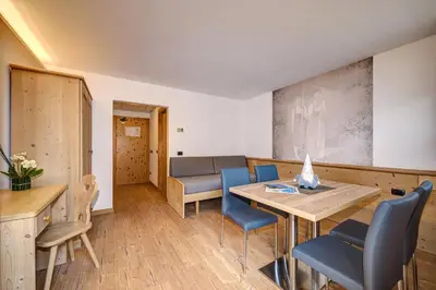 a dining room with a table and blue chairs at Aparthotel Wellness Villa di Bosco in Tesero