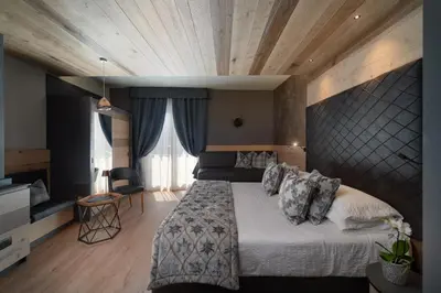 a bedroom with a large bed with a wooden ceiling at Brunet - The Dolomites Resort in Fiera di Primiero