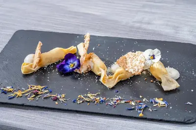 a plate of food with flowers on a table at Brunet - The Dolomites Resort in Fiera di Primiero