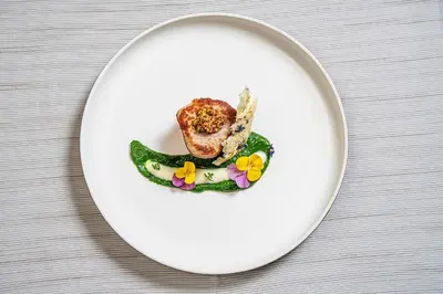 a white plate with food on a table at Brunet - The Dolomites Resort in Fiera di Primiero