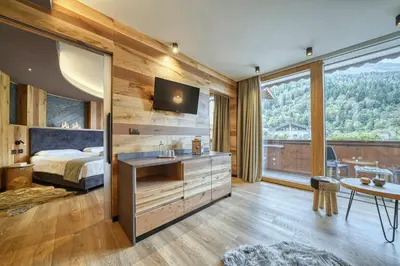 a bedroom with a bed and a large window at Brunet - The Dolomites Resort in Fiera di Primiero