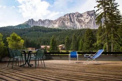 a table and chairs on a deck with a mountain at Residence Grand Hotel Carezza in Nova Levante