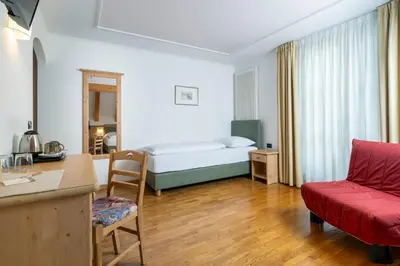a hotel room with a bed and a red couch at Hotel Erica in Tesero