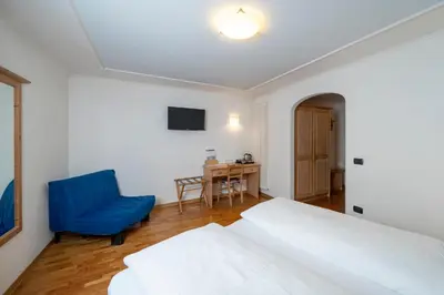 a bedroom with a bed and a blue chair at Hotel Erica in Tesero