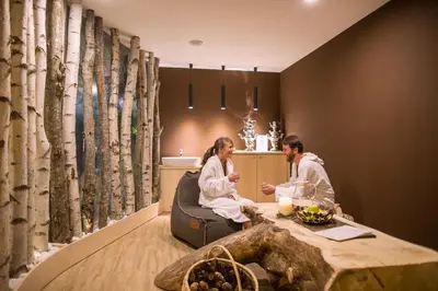 a man and woman sitting at a table in a kitchen at Hotel Erica in Tesero
