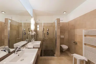 a bathroom with a sink and a shower and a toilet at Hotel Mandelhof in Appiano sulla Strada del Vino