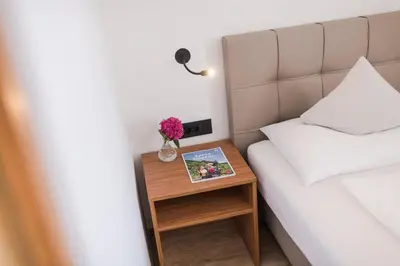 a bed and a table with a vase of flowers on it at Hotel Mandelhof in Appiano sulla Strada del Vino