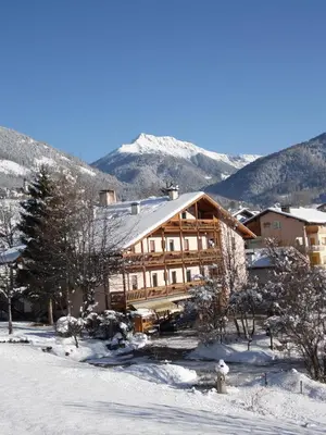 a large wooden building in the snow with a fire hydrant at Albergo Bellaria in Carano