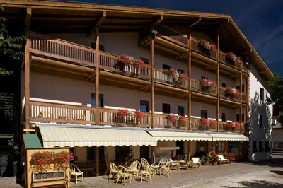 a building with a balcony with tables and chairs at Albergo Bellaria in Carano