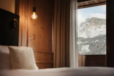 a bedroom with a window with a mountain view at Diana Dolomites in La Villa