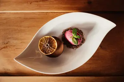 a white plate with two desserts on a table at Diana Dolomites in La Villa