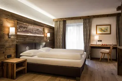 a hotel room with two beds and a desk at Diana Dolomites in La Villa