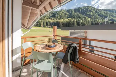 a balcony with a table and chairs and a view of a field at Supperior Appartement in Rasùn di Sotto