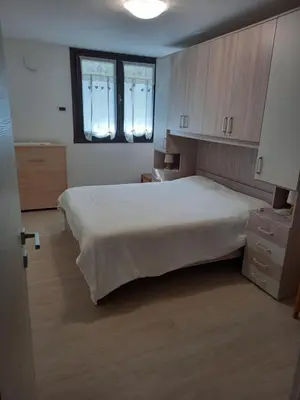 a bedroom with a large white bed and two windows at Casa con vista a Moena in Moena