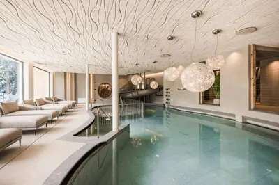 a swimming pool in a building with a lobby at Excelsior Dolomites Life Resort in San Vigilio Di Marebbe