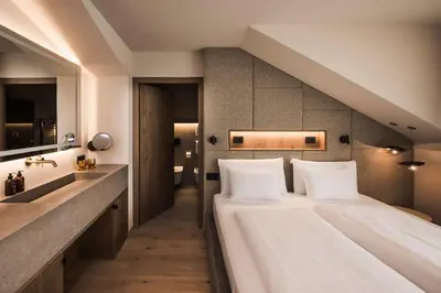 a bedroom with a large bed and a sink at Excelsior Dolomites Life Resort in San Vigilio Di Marebbe