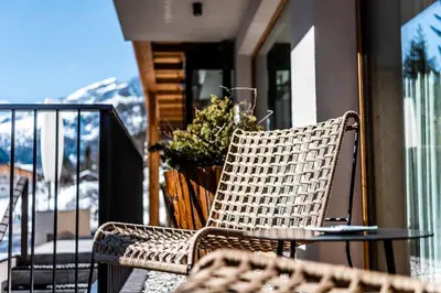 a wicker chair sitting on a balcony with a table at Garni La Ciasota 3s in La Villa