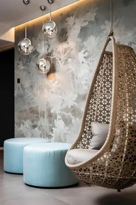 a wicker hammock chair in front of a floral wall at Garni La Ciasota 3s in La Villa