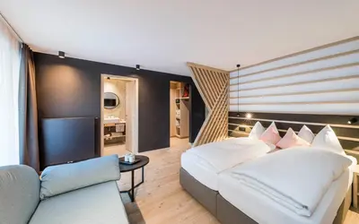 a bedroom with a white bed and a couch at Garni La Ciasota 3s in La Villa
