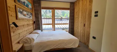 a bedroom with a bed and a large window at Appartamenti Home Service in Arabba