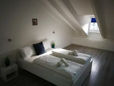 a white bedroom with two beds and a window at Iceman Room's Central in Bolzano