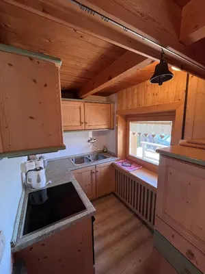 a small kitchen with wooden cabinets and a window at Chalet Biancaneve - Alpe Cermis Cavalese in Cavalese