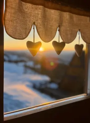 a window with hearts on the curtains with the sunset at Chalet Biancaneve - Alpe Cermis Cavalese in Cavalese