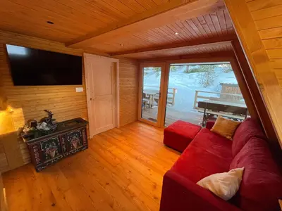 a living room with a red couch and a flat screen tv at Chalet Biancaneve - Alpe Cermis Cavalese in Cavalese