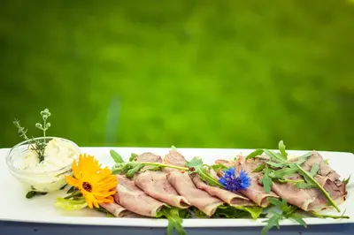 a plate of food with meat and flowers on it at Pension Schlaneiderhof in Meltina