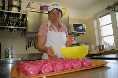 a woman in a kitchen preparing a pile of onions at Pension Schlaneiderhof in Meltina