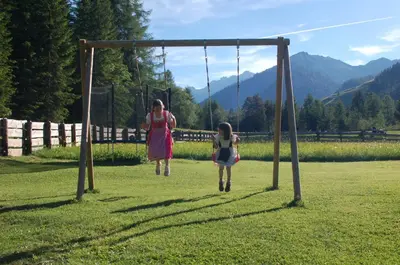 two girls playing on a swing in a field at Agriturismo Feur Hof in San Martino in Badia