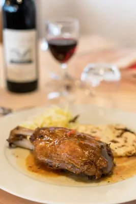 a plate with a piece of meat and a glass of wine at Hotel Canada in Predazzo