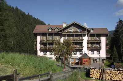 a large white building on the side of a hill at Hotel Canada in Predazzo