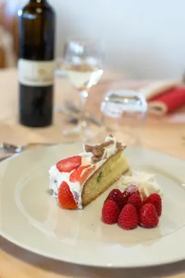 a piece of cake with strawberries on a white plate at Hotel Canada in Predazzo