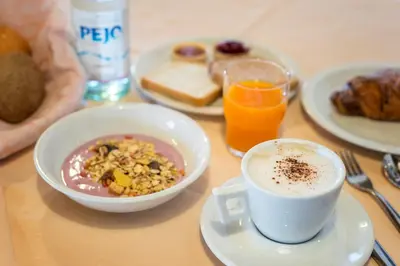 a table with a bowl of food and a cup of coffee at Hotel Canada in Predazzo