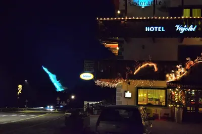 a hotel with christmas lights on a street at night at Hotel Vajolet in Mazzin