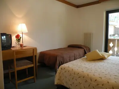 a hotel room with two beds and a television at Hotel Vajolet in Mazzin