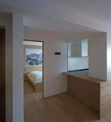 a room with a bed and a kitchen with a mirror at Apartments Thaler Irina in Ortisei