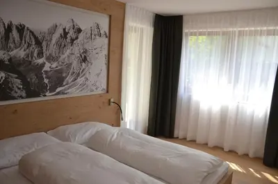a bedroom with a bed with a picture on the wall at Apartments Thaler Irina in Ortisei
