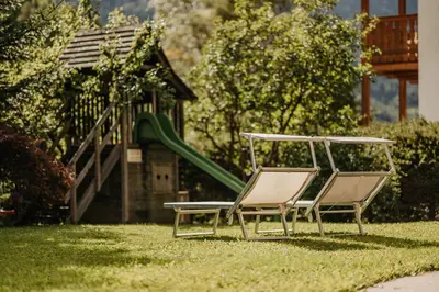 two lawn chairs and a slide in a yard at Apartments Thaler Irina in Ortisei
