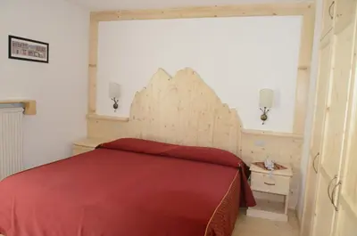 a bedroom with a bed with a red bedspread at Hotel Corona in Carano