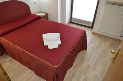 a bed with a red comforter with a box on it at Hotel Corona in Carano