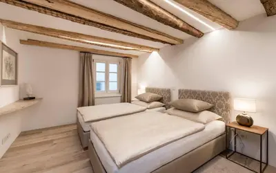 two beds in a room with white walls and a window at Apartment Valentina in Bressanone