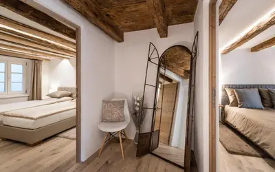 a bedroom with a mirror and a bed and a bed and a chair at Apartment Valentina in Bressanone
