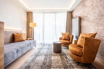 a living room with a couch and a chair at Quellenhof Luxury Resort Passeier in San Martino