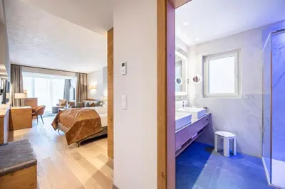 a hotel room with a bed and a bathroom at Quellenhof Luxury Resort Passeier in San Martino